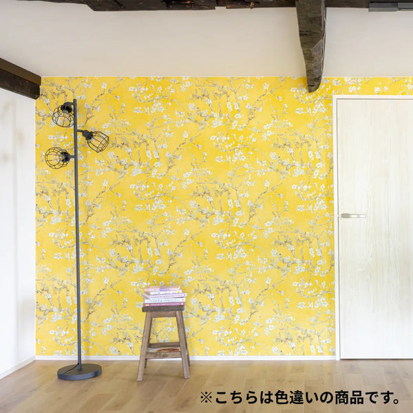 黄色の花柄壁紙を一面に施工したアクセントウォールの室内イメージ。木の床と白いドアのあるナチュラル空間。